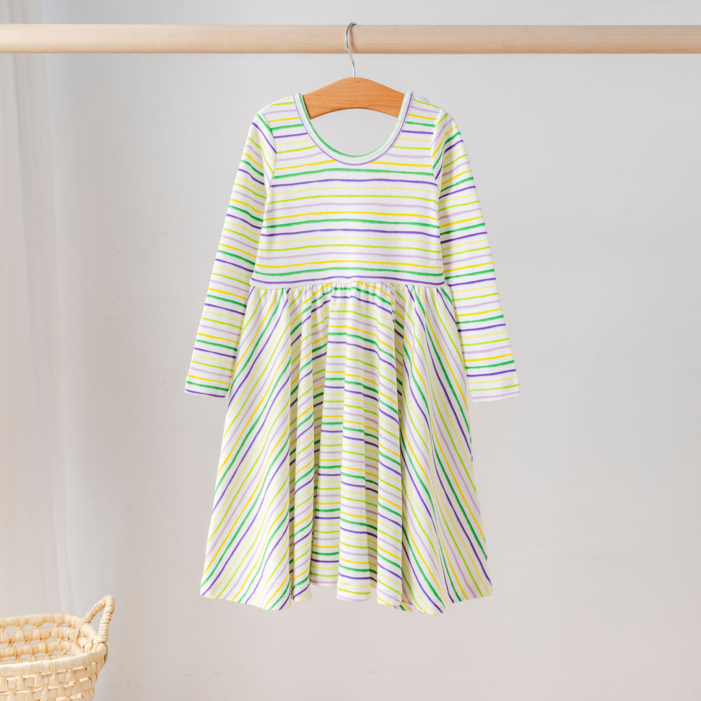 Organic cotton long-sleeve girls’ twirl dress with Mardi Gras striped print in purple, green, and gold. Eco-friendly kids clothing for festive celebrations.