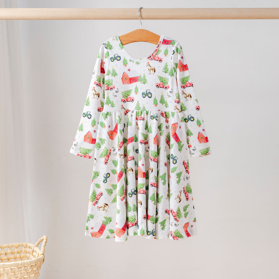 Organic cotton long-sleeve girls’ twirl dress with festive farm print featuring red barns, tractors, Christmas trees, and animals. Eco-friendly kids holiday clothing